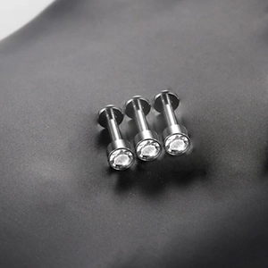 Macro shot of three silver G23 titanium labret studs with clear round zircons on black leather