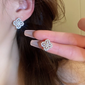 Detail shot of clover stud earrings with sparkling cubic zirconia on model ear