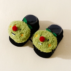 Detailed view of baby non-slip socks with green plush pumpkin character and knit texture