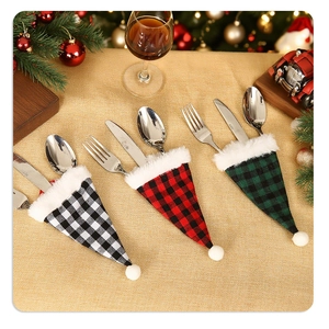 Detail of Christmas buffalo plaid cutlery holders with white plush trim on gold tablecloth