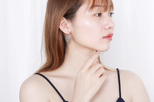 Close-up of woman wearing silver hollow-out pattern metal hoop earrings on white background