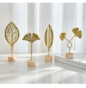 Close-up of golden iron ginkgo leaf sculptures on wooden bases for modern home decor