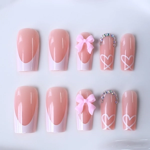 Pink and white French tip press-on nails with 3D bows, heart patterns and rhinestones