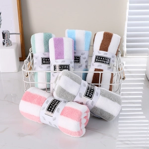 Set of colorful striped coral fleece towels in a basket on marble surface