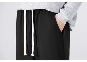 Close-up of black casual trousers featuring an elastic waistband and white drawstring cord