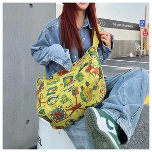 Detailed outdoor shot of a large yellow canvas crossbody bag with retro graphic prints