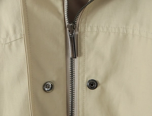 Close-up of the silver metal zipper and snap buttons on the khaki vintage trench coat