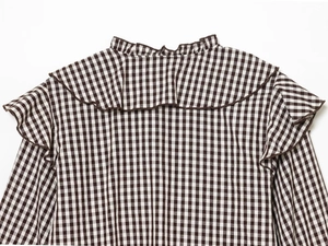 Detailed view of plaid shirt featuring ruffled neckline and pleated back design