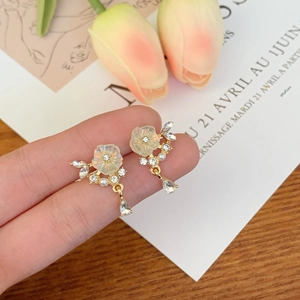 Close-up of floral clip earrings with iridescent petals and teardrop crystal detail