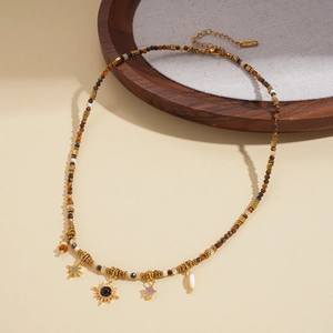 Detail of beaded necklace featuring golden sun, star charms and brown tiger eye stone beads