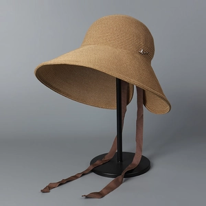 Detailed close-up of woven straw texture and dark brown silk ribbon on sun hat