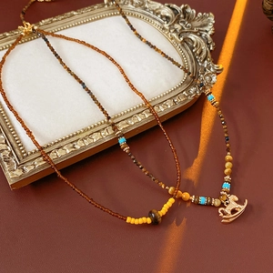 Close-up of vintage tiger eye necklaces with golden horse pendant on a red background
