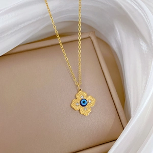 Close-up of gold clover pendant with blue evil eye detail and crystal accents