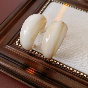 Detail view of C-shaped resin earrings with brown marble texture on vintage wooden frame