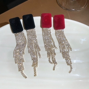 Dettaglio di orecchini floccati rossi e neri con frange di strass brillanti e nappe
