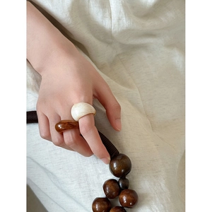 Close-up of amber and cream resin rings worn by a model in a minimalist natural style