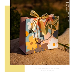 Detail of oil painting floral gift bag with gold ribbon on a natural stone surface