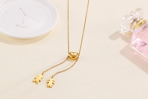 Détail du collier ajustable avec fermoir cœur et silhouettes d'enfants en métal doré poli