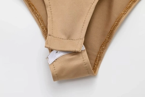 Detail van het kruis van de elastische bodysuit met drievoudige drukknoopsluiting