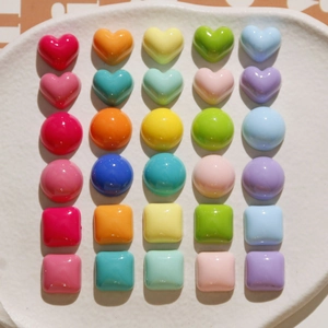 Close-up of heart and round macaron resin charms on a white ceramic plate
