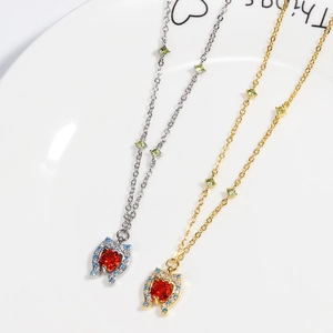 Detail of a horseshoe pendant necklace with red heart stone on a white ceramic plate