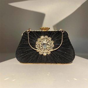 Close-up of black pleated evening bag featuring a large sparkling rhinestone floral buckle