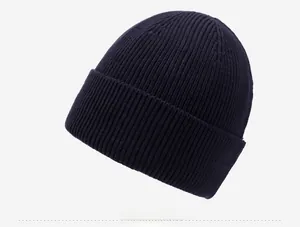 Détail du bonnet en tricot bleu marine montrant la texture côtelée et le logo métallique