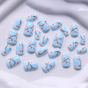 Short light blue press-on nails set with pink cherry blossoms and gold glitter accents
