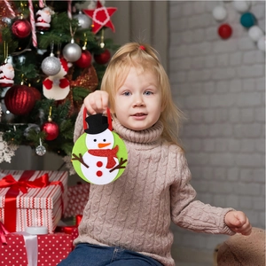 Close-up of a green felt Christmas gift bag featuring a 3D snowman held by a child