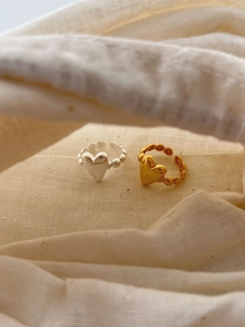 Close-up of gold and silver heart bubble rings with adjustable open band design