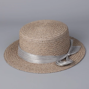 Close-up of a raffia boater hat showing woven texture and silk bow detail on grey background