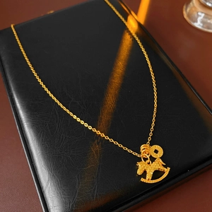 Close-up of gold-plated pony pendant necklace with textured finish and lucky coin detail