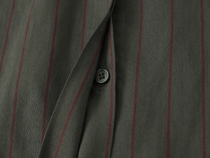 Macro detail of dark grey fabric with slim red stripes and a black button on the shirt