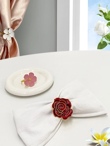 Detail of floral enamel napkin rings featuring white, pink, and red rose designs for decor