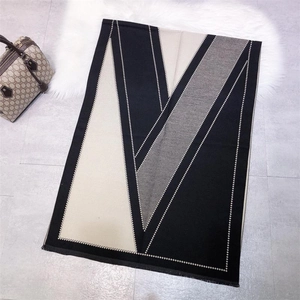 Detail of cashmere-like scarf showing black white and grey geometric knit and fringe