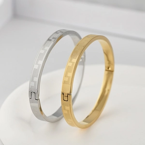 Detail of gold and silver stainless steel bangles with etched geometric patterns