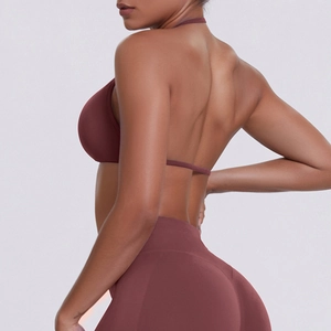 Detail of cross-back halter sports bra and high-waist leggings in rust red matte fabric