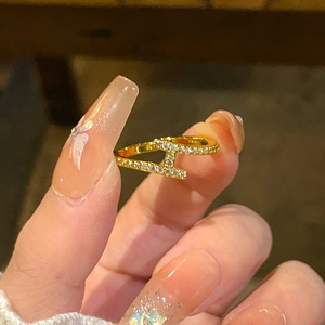 Bague en forme de H plaquée or avec pierres en zircone portée sur la main d'une femme