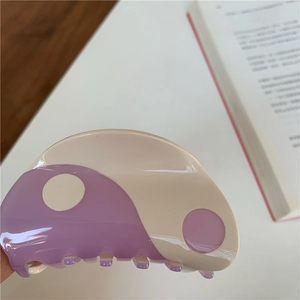 Detail of yin yang hair claw clip in purple and cream white with a glossy finish