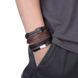 Gros plan de bracelets multicouches en cuir tressé avec un pendentif guitare vintage