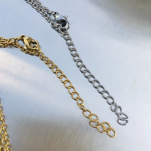 Macro detail of gold and silver lobster clasps with metal extension chains on texture