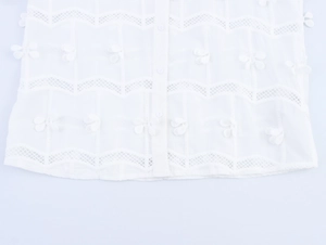 Dettaglio camicia bianca con strisce a rete traforate e piccoli fiocchi decorativi