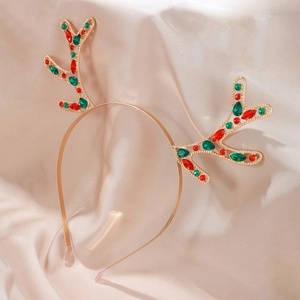Detail of golden metal reindeer antler headband featuring festive red and green gemstones