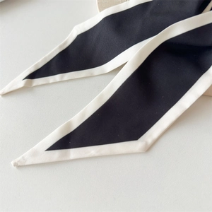 Detail of elegant black and white bow hair tie featuring smooth satin ribbon texture