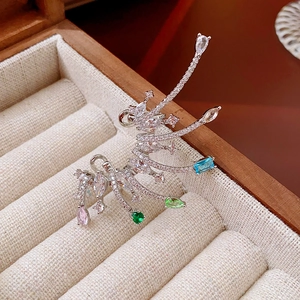 Detailed close-up of silver wing ear cuff with multi-color zircon in beige jewelry box