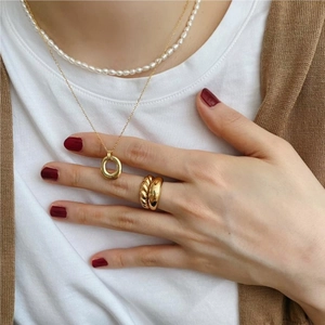Layered gold necklace with ring pendant and pearl choker set on a model