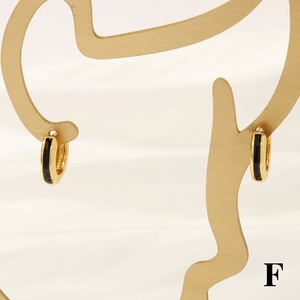 Detail of 18K gold hoop earrings with black enamel on a gold silhouette display
