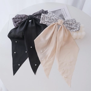 Detail of floral ribbon hair clips in black and beige with delicate pearl embellishments