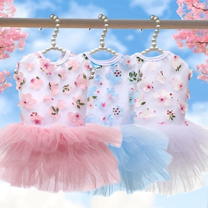 Three colors of floral tulle pet dresses hanging on pearl hangers with cherry blossoms