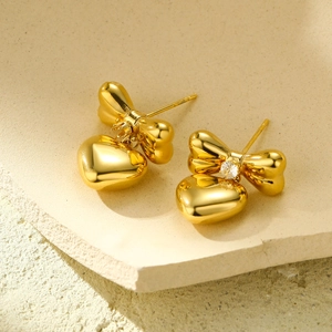 Elegant gold bow and heart stud earrings with zircon stone on stone background